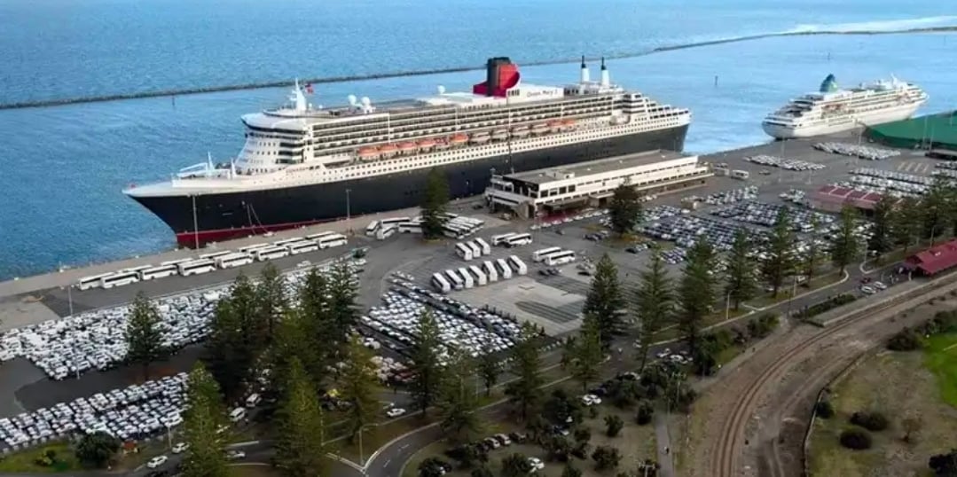 Aerial view of the Outer Harbor cruise terminal in Adelaide with Queen Mary 2 at the berth, a second cruise ship beyond and the Outer Harbor railway line in the foreground